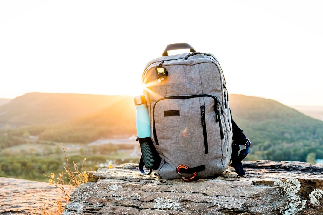 A neatly packed backpack with travel essentials organized inside, set against a scenic outdoor backdrop.